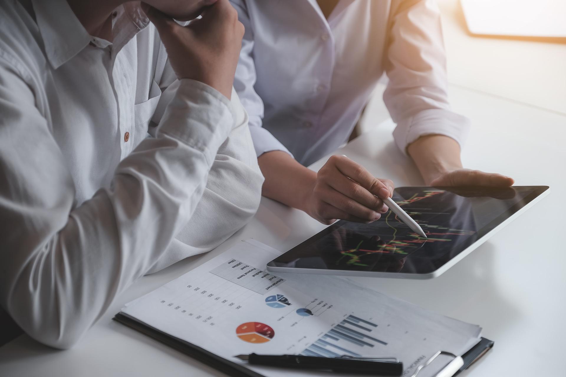 Team analysiert Finanzgrafik am Tablet | Gewerbeimmobilien Stuttgart

