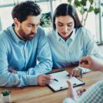 Zwei Mitarbeitende in einem Gespräch mit einem Berater - Symbolbild für Familienservice im Unternehmenskontext